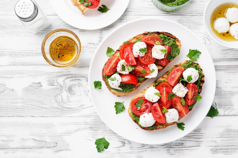 Bruschetta,With,Cherry,Tomatoes,,Mozzarella,Cheese,And,Pesto,Sauce,On