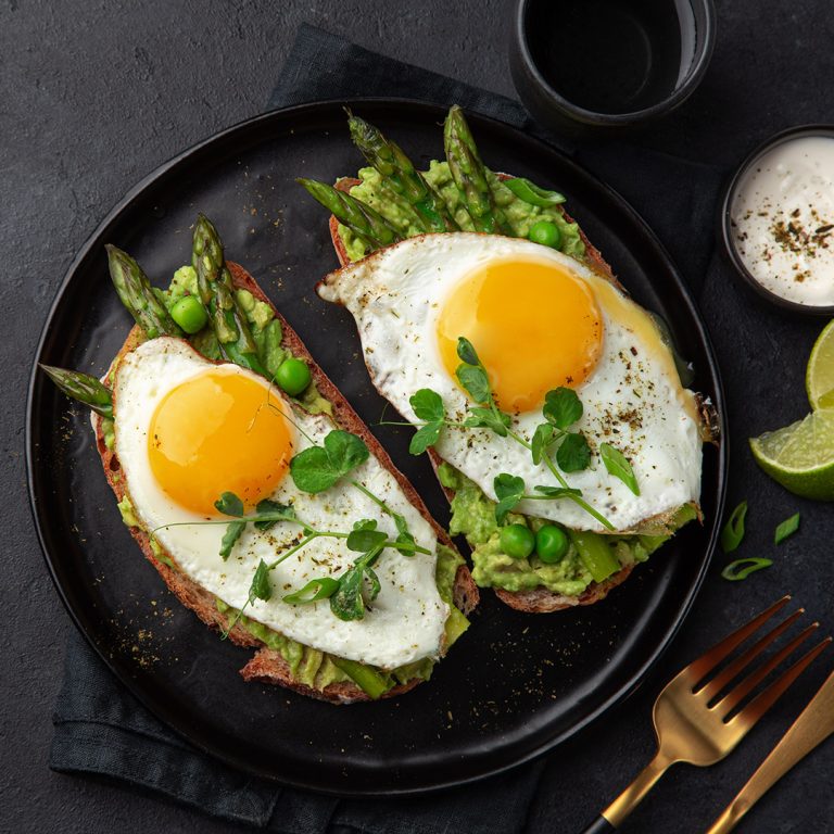 Toasts,With,Avocado,,Asparagus,And,Fried,Egg,On,Black,Plate,