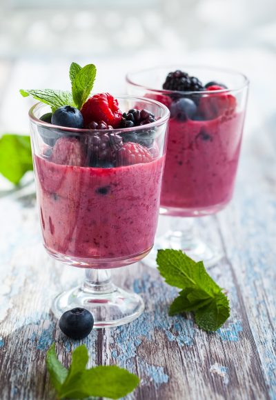 Delicious blackberry,raspberry and blueberry smoothie garnished with fresh berries in glasses