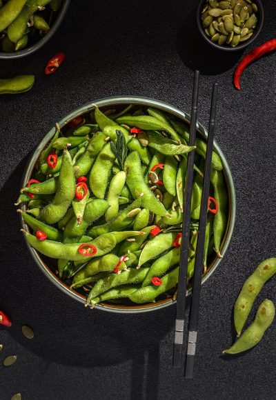 edamame bean salad in pods with chili pepper on a black background