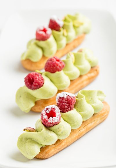 Traditional french eclair with pistachio cream and strawberries on white background