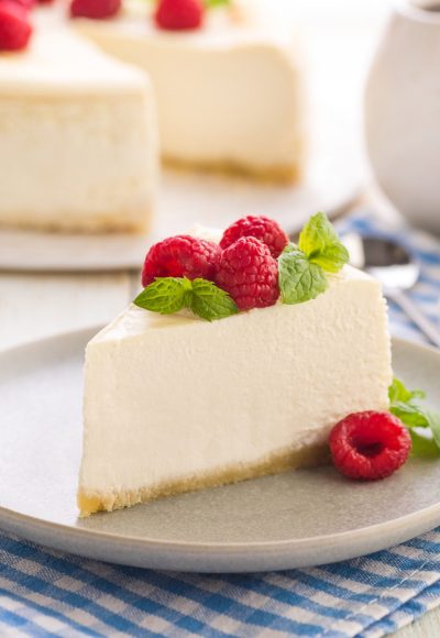 Cheesecake. Traditional american dessert. A large piece of cake with raspberries and fresh mint leaves. Ready to eat