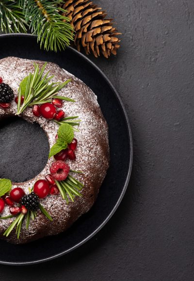 Christmas cake decorated with pomegranate seeds, cranberries and rosemary. Flat lay with copy space