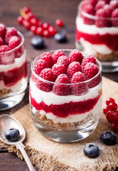 Raspberry dessert, cheesecake, trifle, mouse in a glass on a wooden background