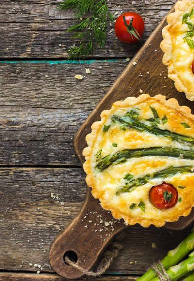 tart with asparagus and cherry tomatoes  on rustic background, top view