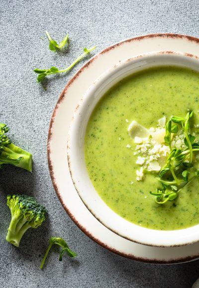 Green soup. Broccoli cream soup with cream and parmesan. Healthy vegan dish. Top view at white table.