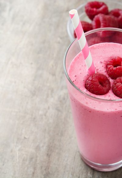 Raspberry smoothie in glass on wooden table