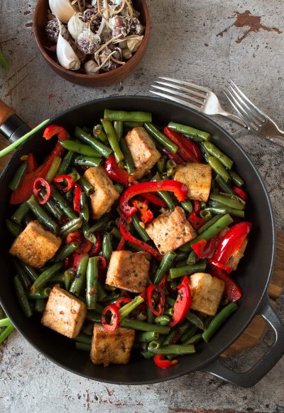 frying pan with fried tofu with green beans and bell peppers on the table