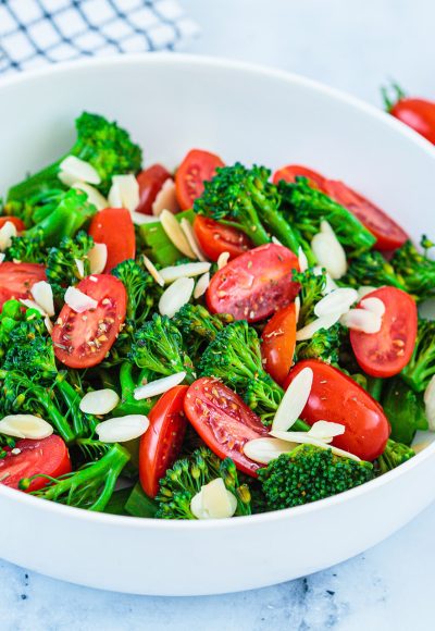 Broccoli salad with cherry tomatoes and almonds in a white bowl. Vegan detox recipe.