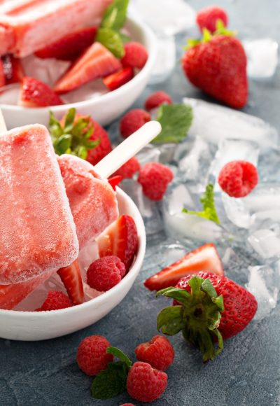 Strawberry and raspberry ice cream popsicles in white bowls