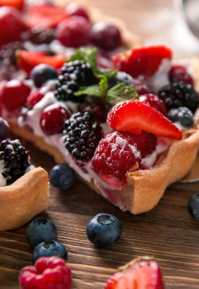 Delicious pie with ripe berries and piece on shovel, closeup