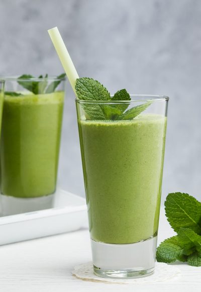 Healthy drink. Smoothies with banana, avocado, spinach, lime on a gray background.