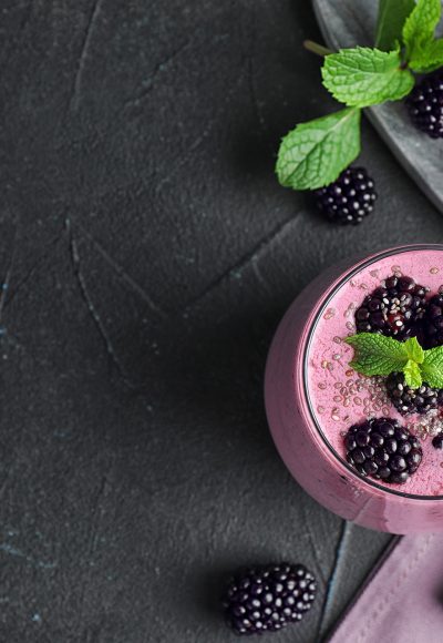 Flat lay composition with glass of delicious blackberry smoothie on black background. Space for text