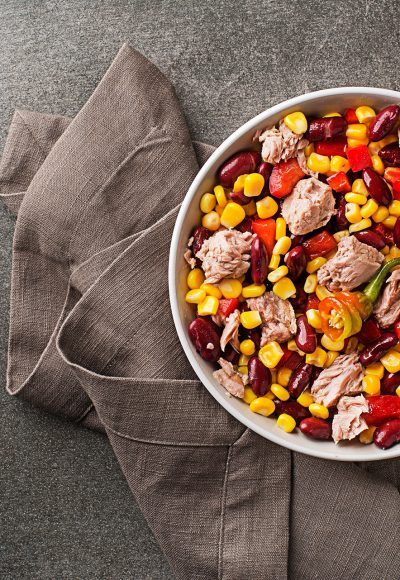 Healthy tuna salad with corn, peppers and beans on grey background. Mexican corn salad.