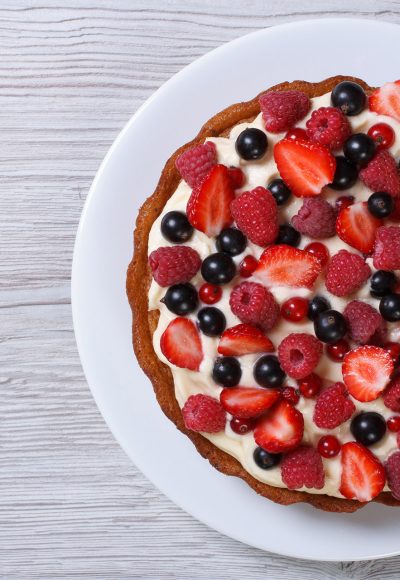 Delicious tart with fresh strawberries, raspberries and currants on the table. top view horizontal